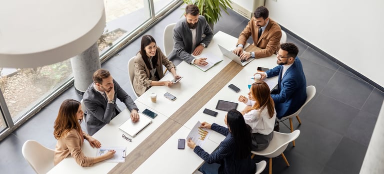 Leadership team from above sitting at conference table in boardroom meeting
