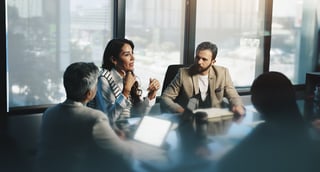 Executive team in boardroom reviewing financial performance data