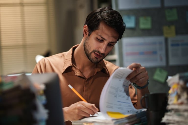 Latin man reviews financial accounting documents, vendor spend analysis